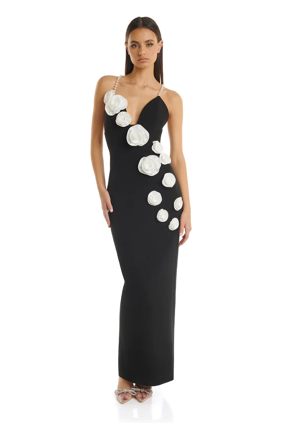 Front view of a black evening dress featuring pearl suspenders, white floral decorations, and a sleeveless design.
