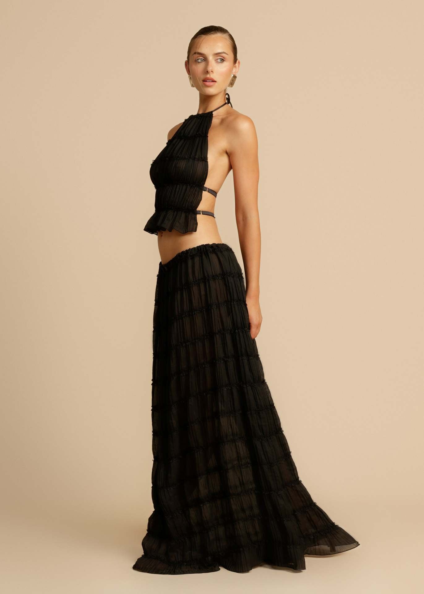 Side view of the Black Chiffon Backless Lace-up Pleated Maxi Dress, highlighting the flowing pleats and flattering silhouette.